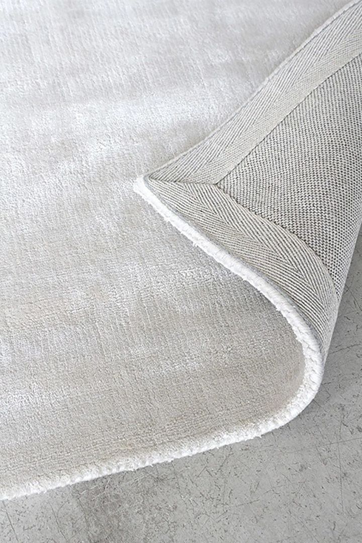 Nærbilde av Solid viskoseteppe i fargen Francis Pearl Beige fra Layered, som gir hjemmet ditt en luksuriøs og varm følelse.