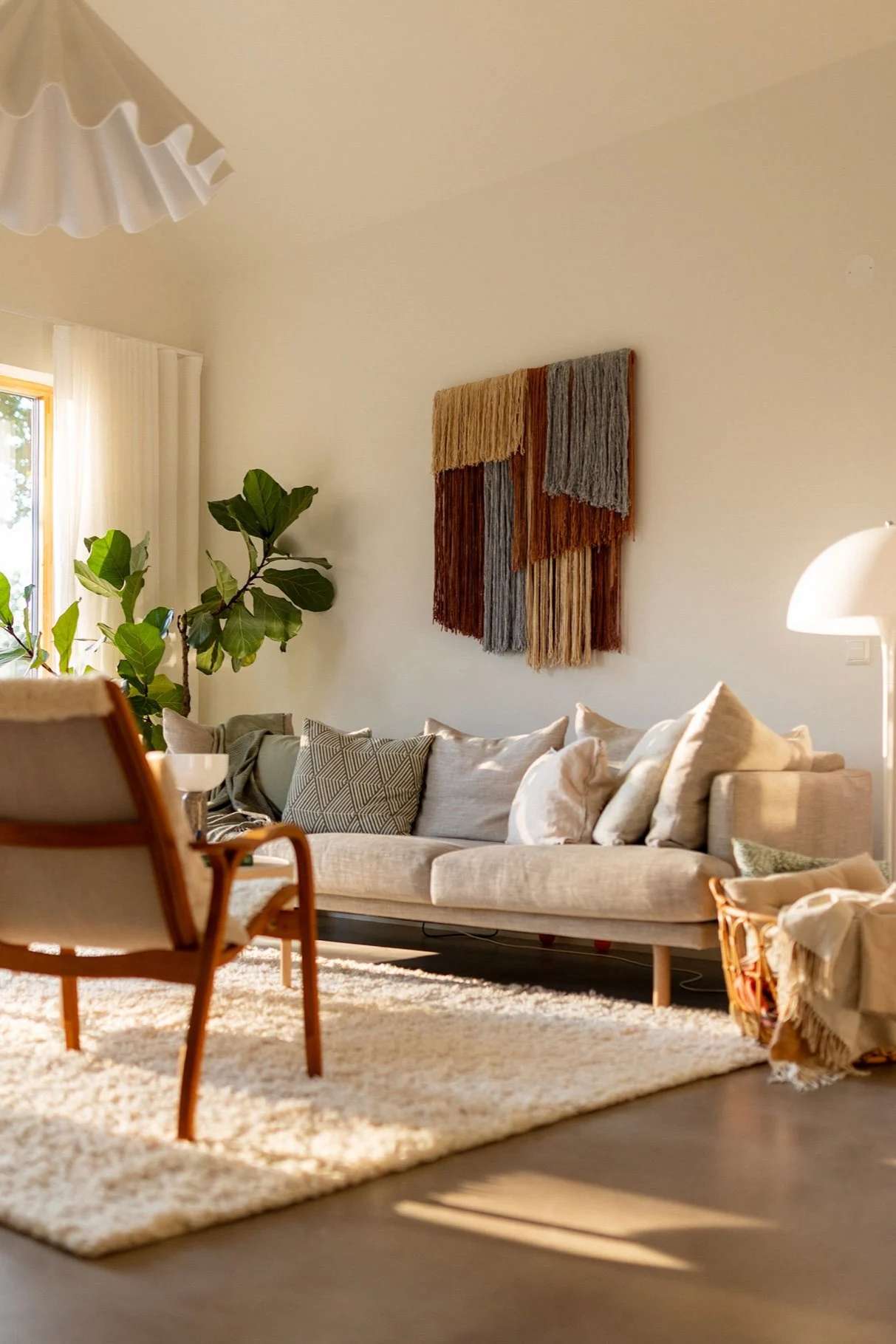 Tham veggdekor i tekstil fra Tinted henger på en vegg i en stue over en sofa.