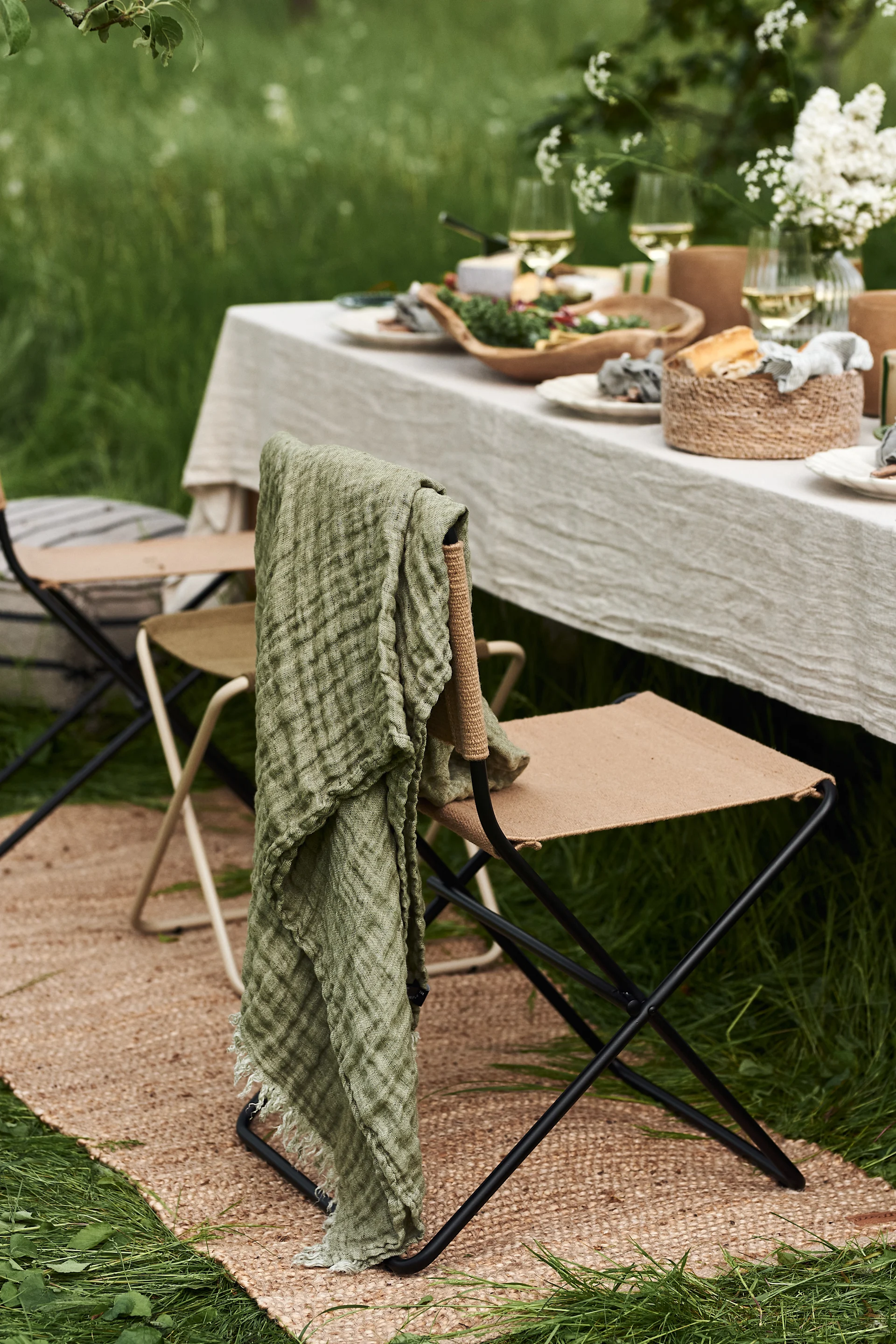 En borddekking til hagefesten blir ikke komplett uten myke tekstiler som dette fine Hannelin-pleddet i grønt fra Himla som blir en fin detalj over stolryggen.