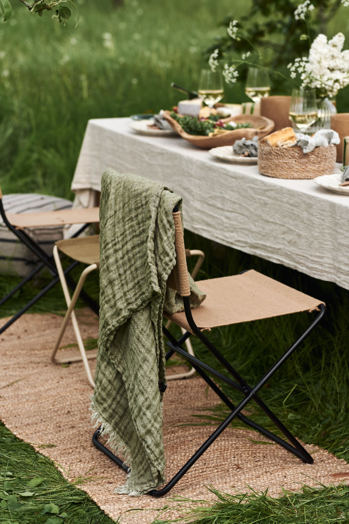 En borddekking til hagefesten blir ikke komplett uten myke tekstiler som dette fine Hannelin-pleddet i grønt fra Himla som blir en fin detalj over stolryggen.