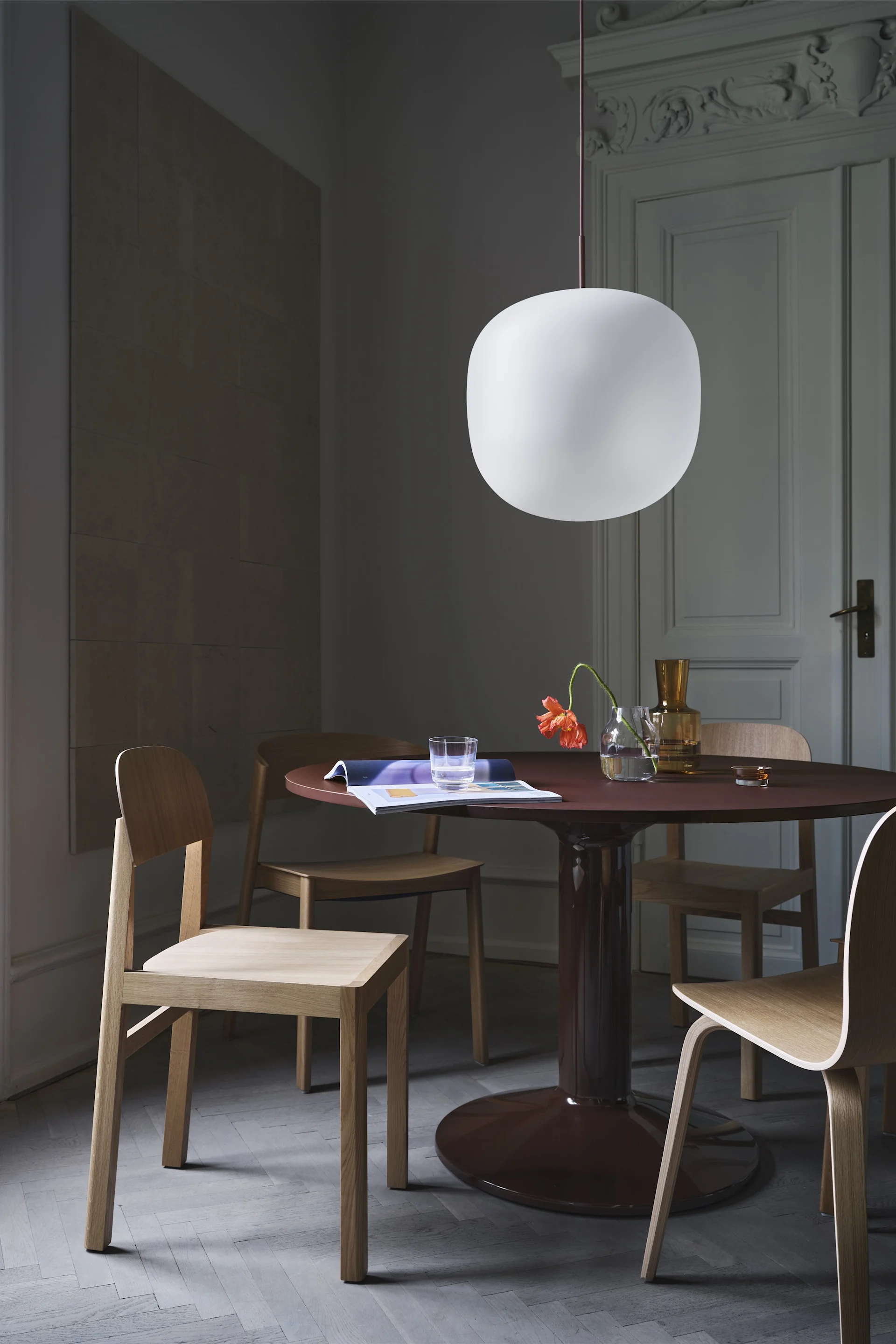 Cover stol er et av Thomas Bentzens mest kjente møbler, her i massiv eik ved siden av mørkerødt, rundt spisebordet.