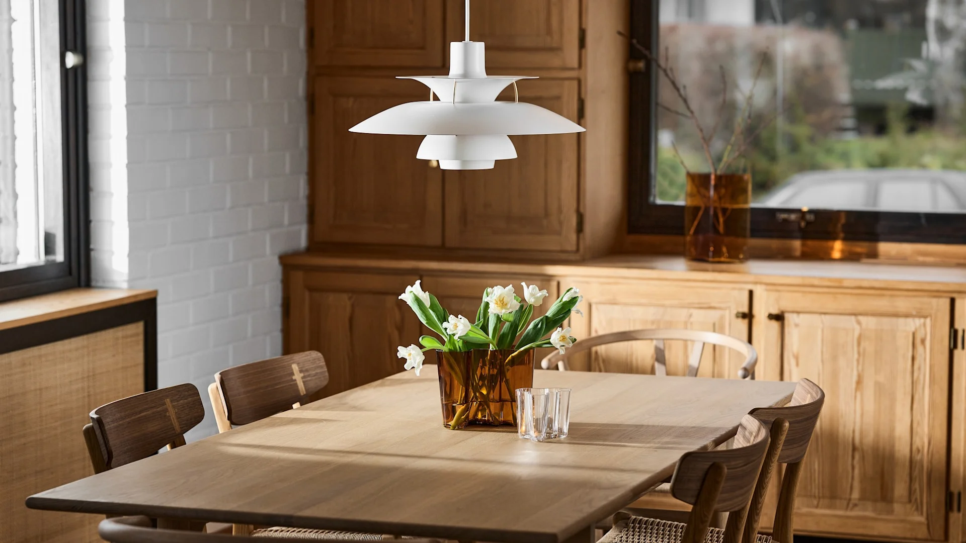 På et spisebord i et kjøkken står Aalto-vasen med påskeliljer.
