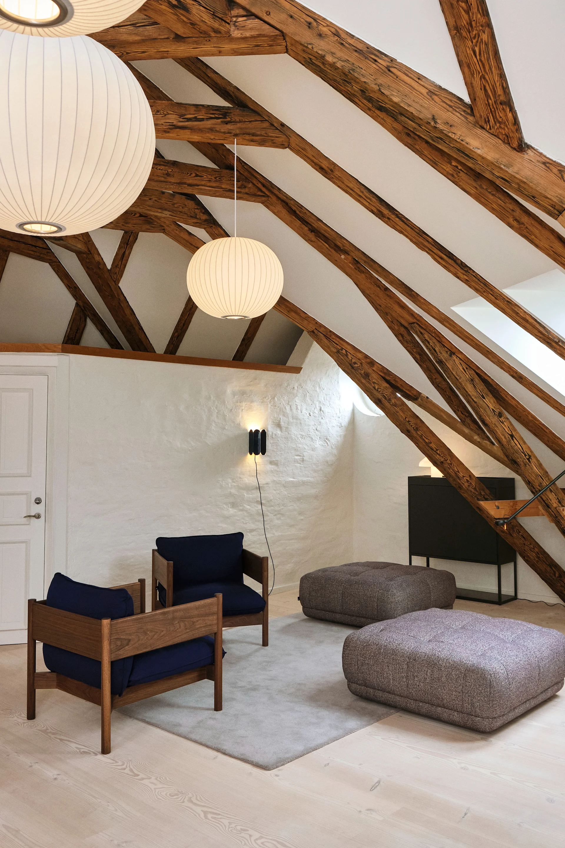 Taklamper til stuen: I en stue med høyt under taket og synlige trebjelker henger flere Nelson Bubble Ball-pendellamper fra Hay.