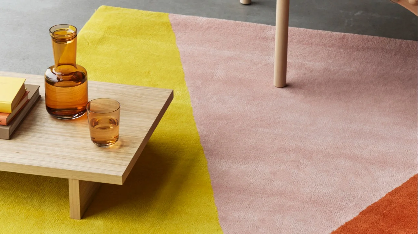 En stue med beige teppe og grønne ullpledd fra NJRD Edges-kolleksjonen.