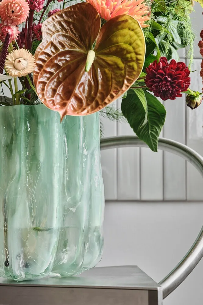 Blå, sprukket vase fra Kosta Boda med en haug med blomster.