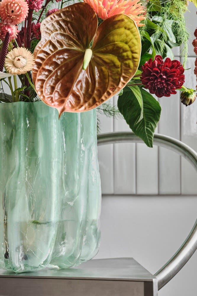 Blå, sprukket vase fra Kosta Boda med en haug med blomster.