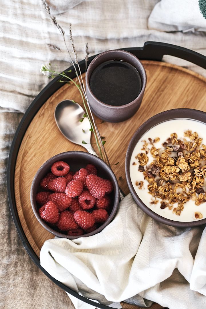 Frokost på senga serveres på et vakkert brett fra Eva Solo med bær og müsli i brune boller fra Ferm Living.