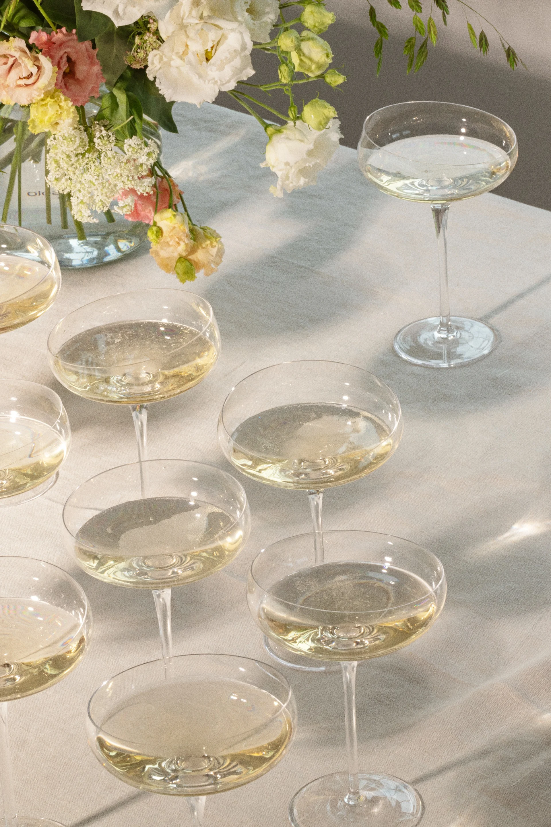 Champagneglass med musserende drikke på et bord med blomsterarrangement.