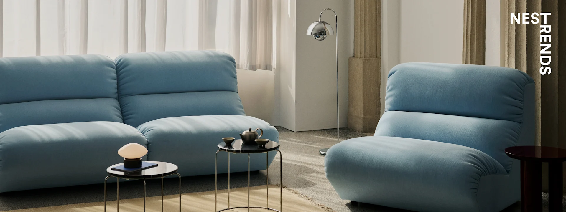 Moderne stue med to lyseblå sofaer, svarte marmorbord og elegante lamper.