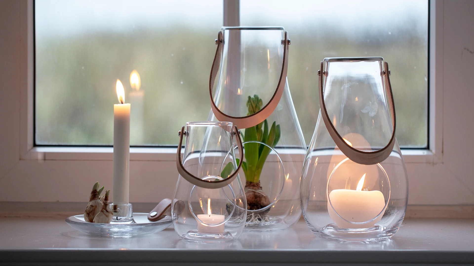 Pynt vinduskarmen: Design with Light-lanternene fra Holmegaard i ulike størrelser står på en vinduskarm.

