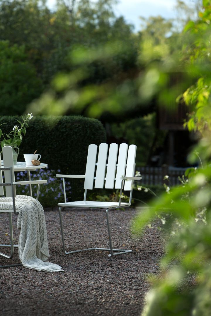 Bli kjent med Grythyttan Stålmöbler, her A2 lenestol i hvitt i hagen.