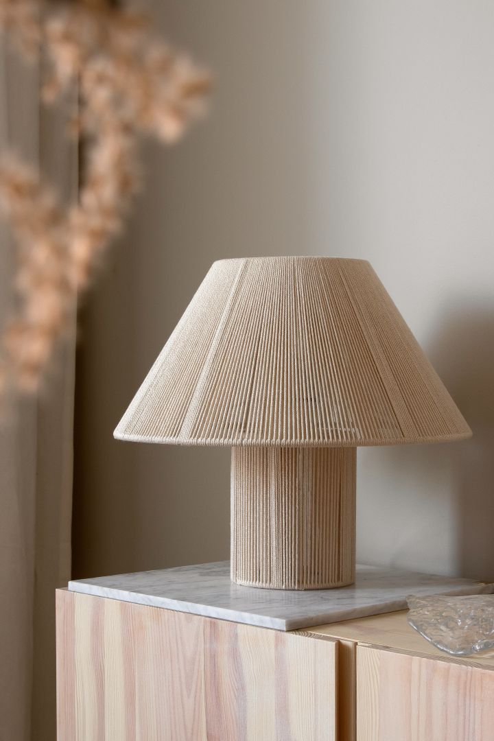 Anna bordlampe fra Globen Lighting er et tips på en trendy lampe med plissert lampeskjerm i beige, som skaper behagelig lys gjennom sine bomullstråder.