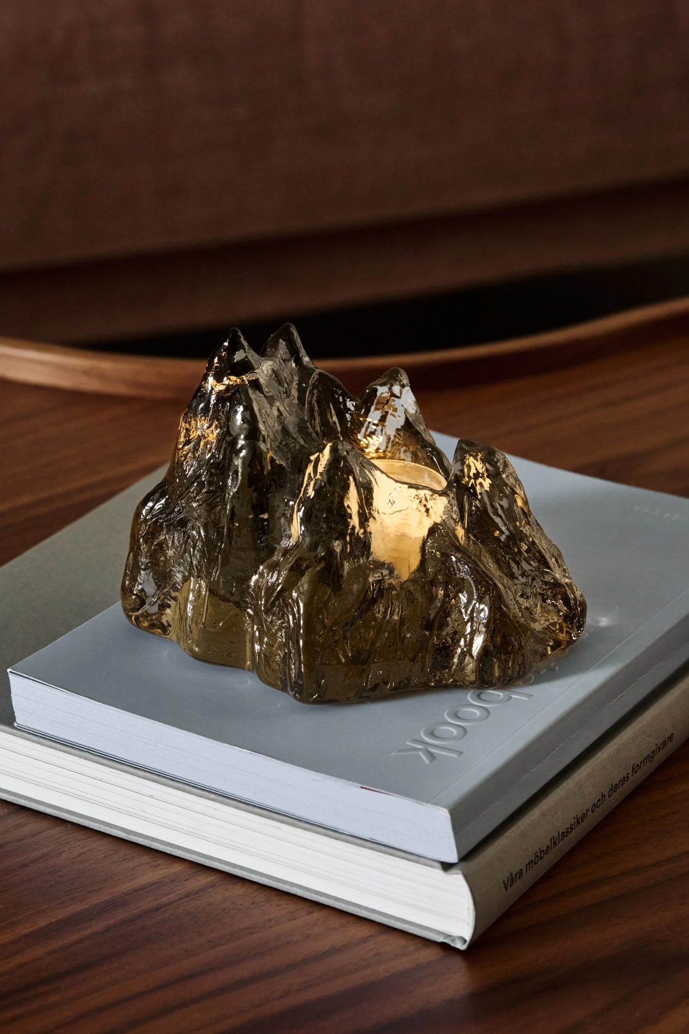 På en pakke fra Nordic Nest står den brune lysestaken The Rock fra Kosta Boda under juletreet.
