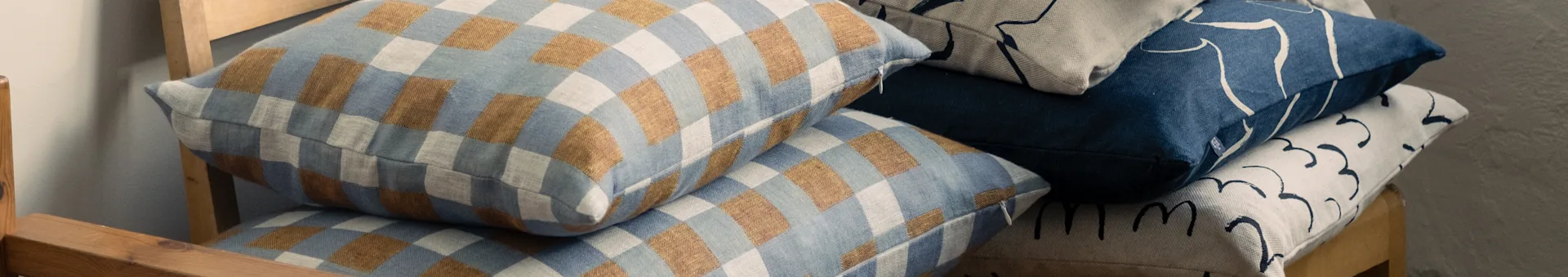 Stablede puter på en trestol, med rutete blå og brune, og abstrakt mønstrede blå og beige design.