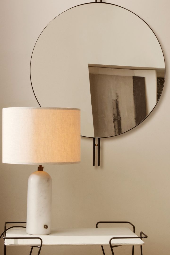 Gravity bordlampe i hvit marmor på et sidebord foran et speil.