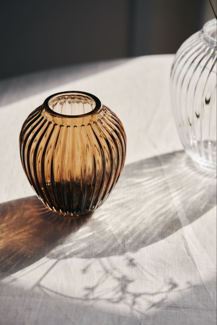 Her kan du se solskinn som skinner gjennom den lille glassvasen i valnøtt og en større klar glassvase fra Kähler’s Hammershøi serie.