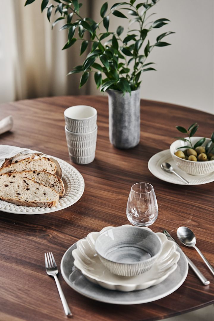En placemat med grå og beige tallerkener, boller, kopper, tallerkener og krukker fra Bubbles, Stripes, MSY, Basic og Oyster serien av Mateus.
