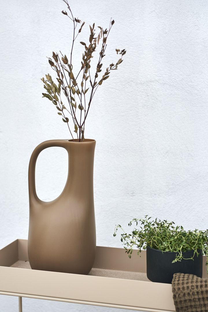 Tips til koselig uteplass - innred uteplassen med planter og grønt. Fyll ferm LIVINGs vannkanne med fine kvister og den kan brukes som vase i stedet.
