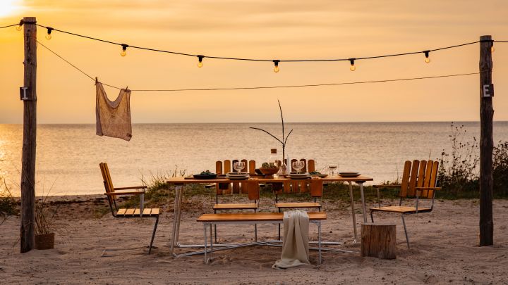 Bli kjent med Grythyttan Stålmöbler, her A2 stoler og A1 bord på stranden ved solnedgang.
