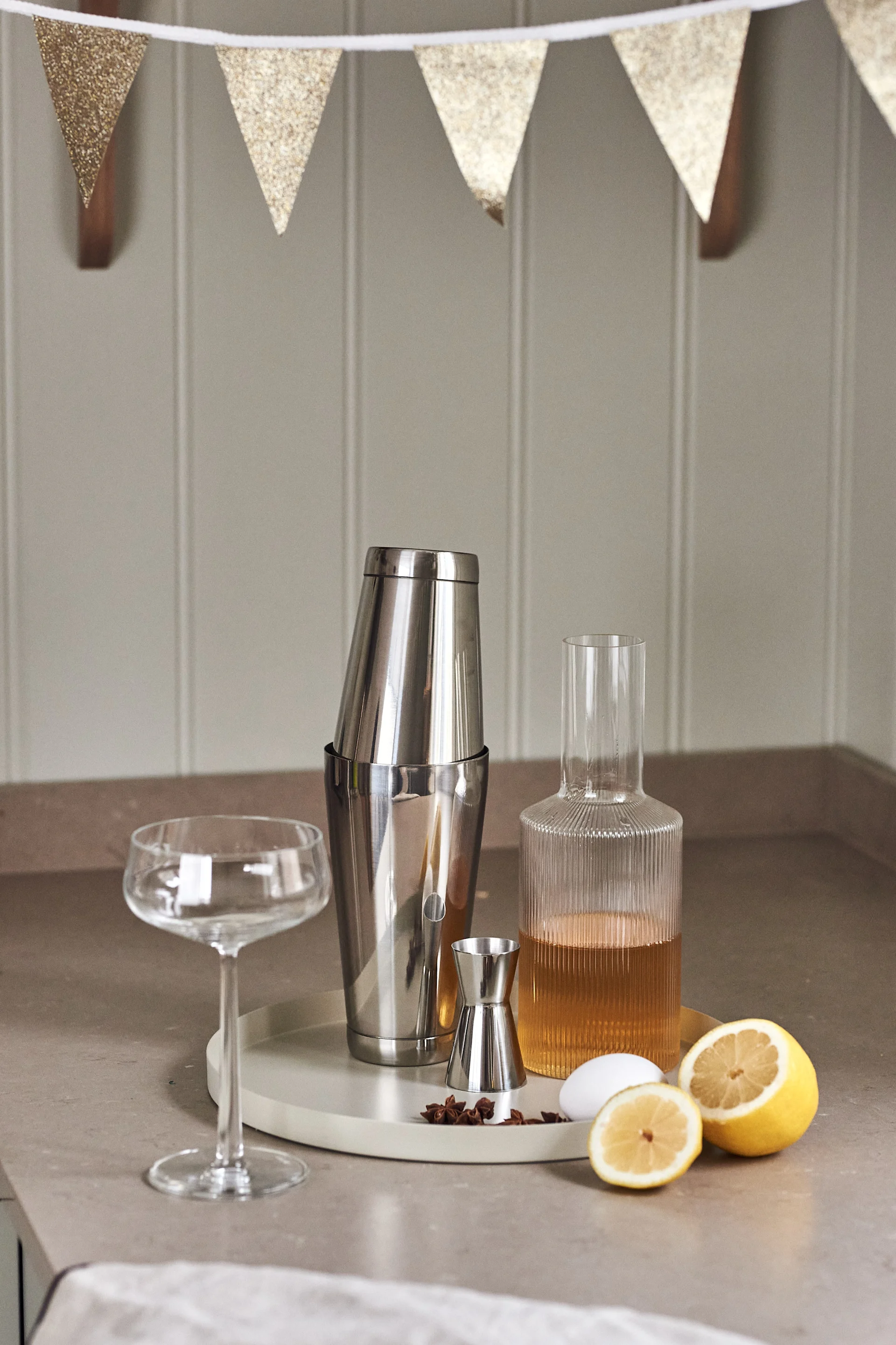4 festlige & enkle drinker til nyttår - her ser du Dorre shaker, Rosendahl måleglass og Ripple karaffel fra Ferm Living på et brett fra Cooee Design.