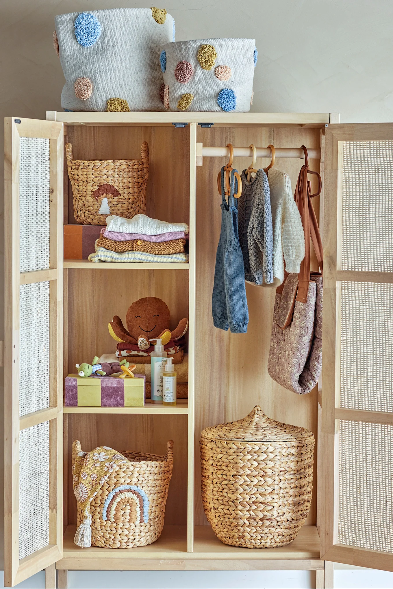 En garderobe i tre fylt med flettede kurver og barneklær. Oppbevaringskurver er en flott gaveidé til babyshower.