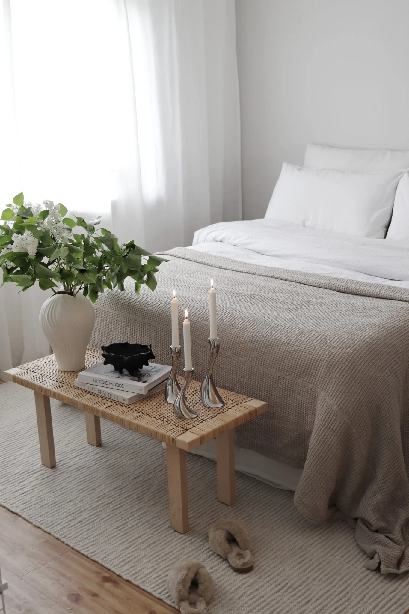 Gulvtepper til soverommet: Det hvite Pebble-ullteppet fra Scandi Living ligger delvis under sengen, og ved fotenden står en liten benk dekorert med en plante og stearinlys. @hemmahosfalk
