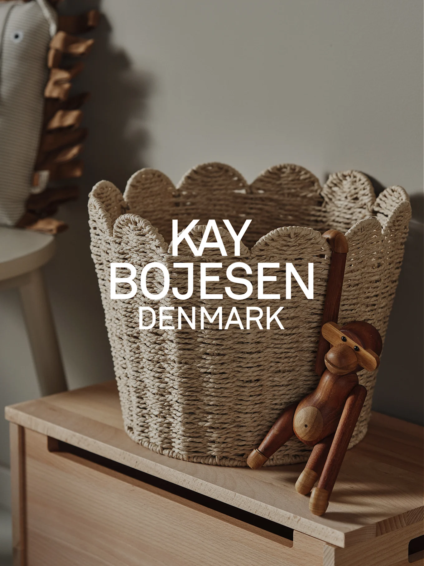 En naturlig flettet kurv med bølgete kanter og en treapekatt henger på et lyst treskap.