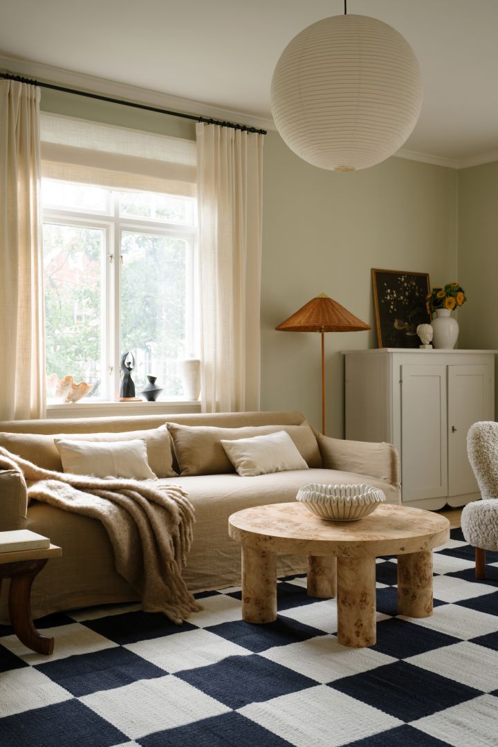 Taklampe stue - bildet viser Rice paper lampeskjerm fra HAY, her hengende i stue med beige sofa, svart-hvitrutete teppe og rustikk salongbord i tre.