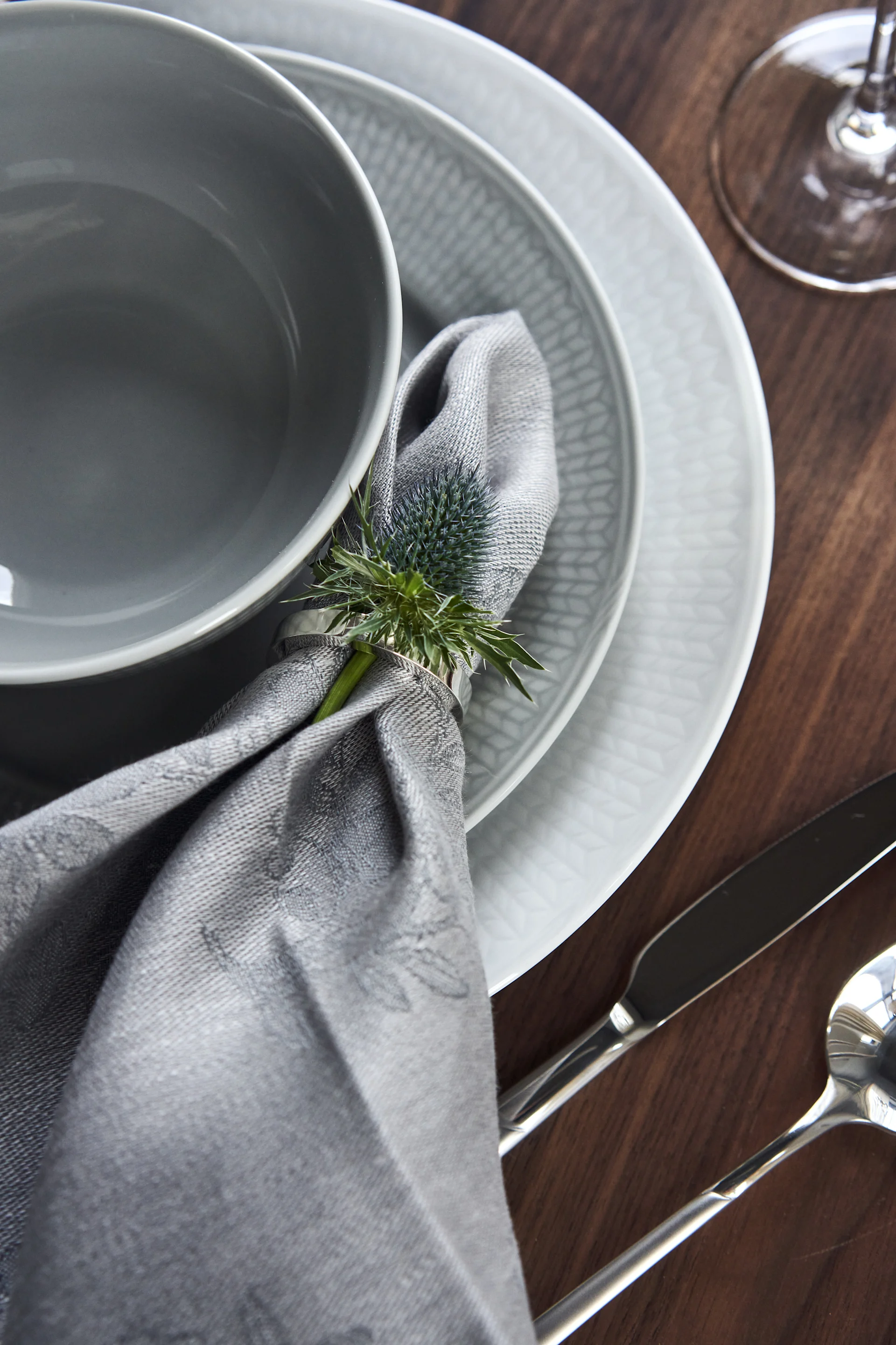 Bordsett med svensk Grace porselen i hvitt og grått og lin serviett i serviettring og blomst.