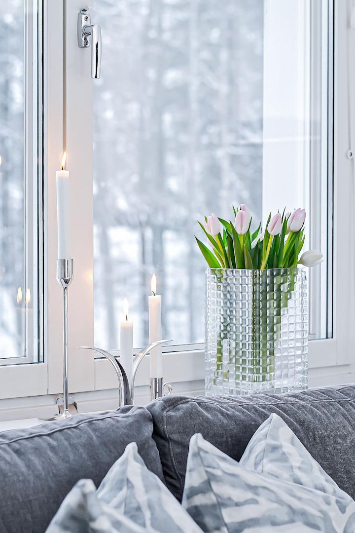 Dekorer vinduskarmen med lys eller vakre blomster, spesielt i de mørkere månedene. Her ser du friske tulipaner i vasen City Hurricane av Louise Roe, ved siden av ulike sølvlysestaker med hvite stearinlys i i vinduskarmen av @josefinsinredning.