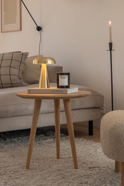 Skap et hjem i skandinavisk stil med @haus_tannenkamp, Her ser du Como bærbare bordlampe på et sidebord i lyst tre.