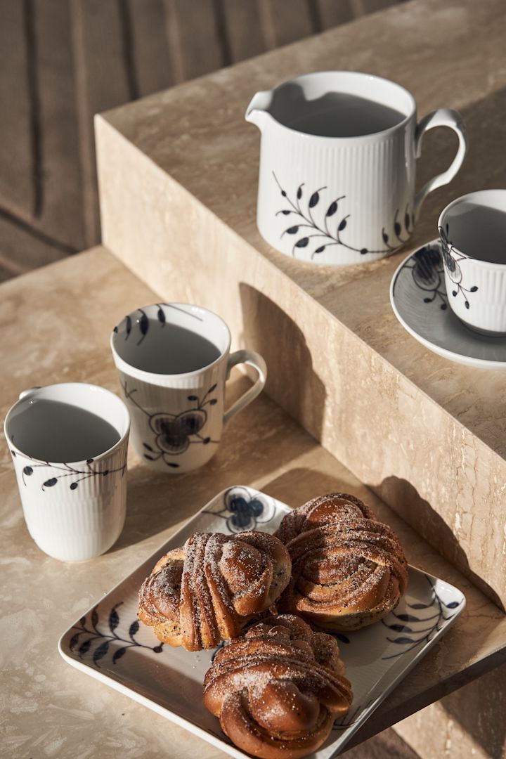 Black fluted mega melkekanne, tallerken med kanelboller og kopp med fat fra Royal Copenhagen i svart og hvitt - perfekt for kaffestunden.