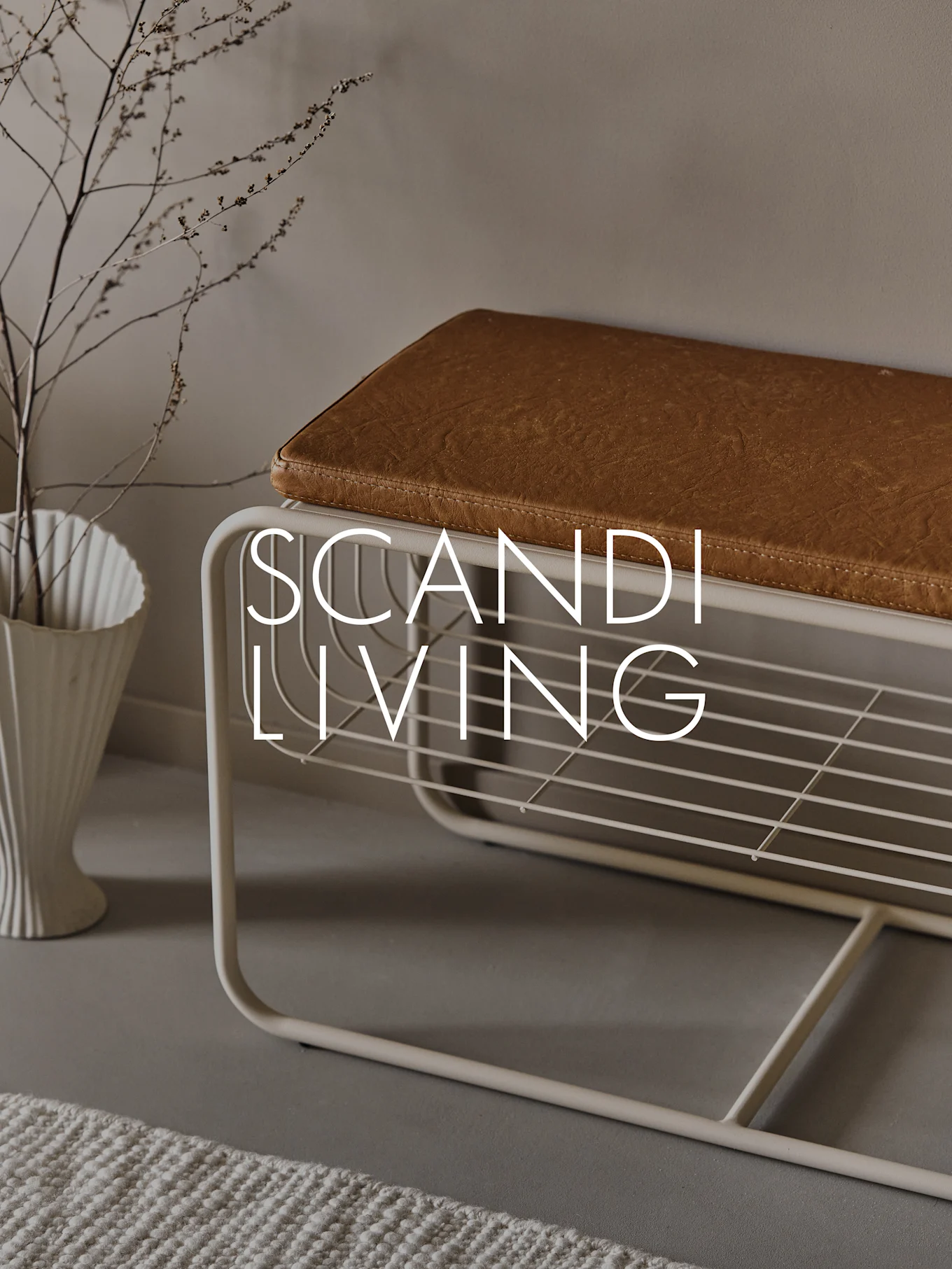 Inngangsbens med brun pute, skohylle, hvit riflet vase med grener og teksten 'SCANDI LIVING'.