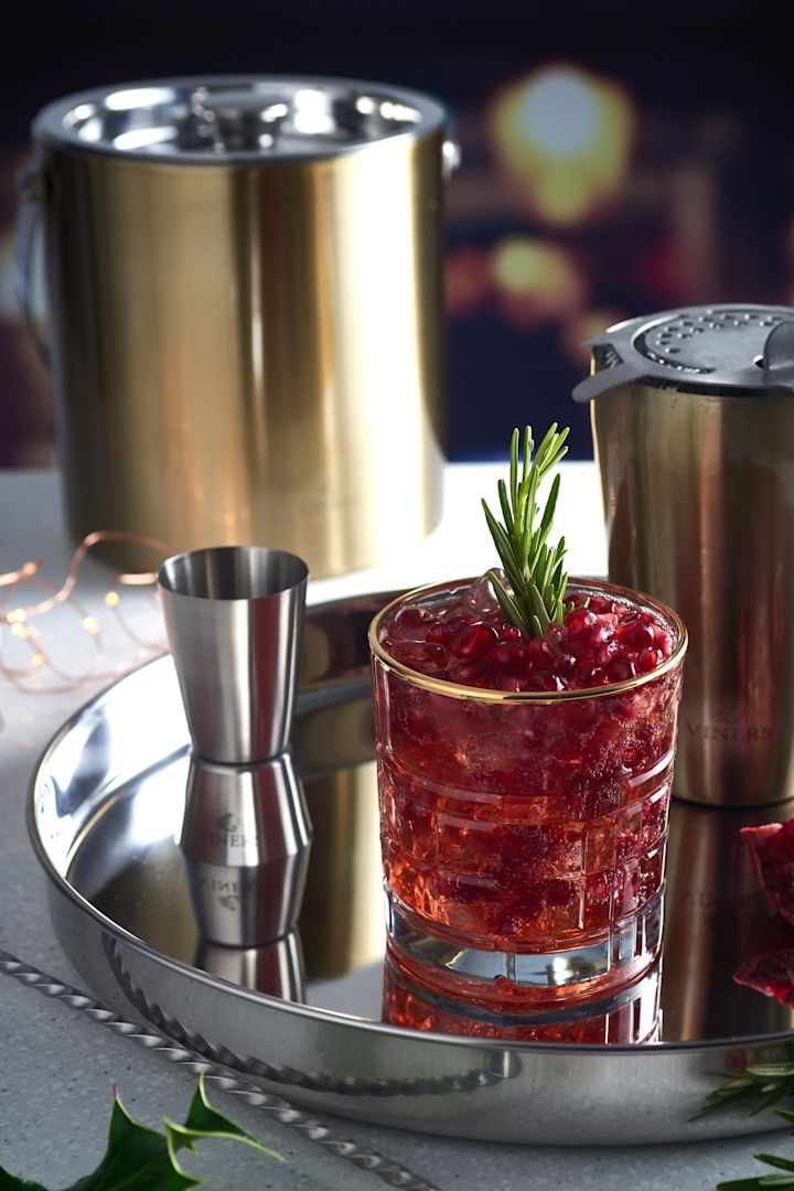 En mocktail står på et sølvfat, omgitt av cocktailutstyr som en shaker og den gyldne isbøtten fra Viners.