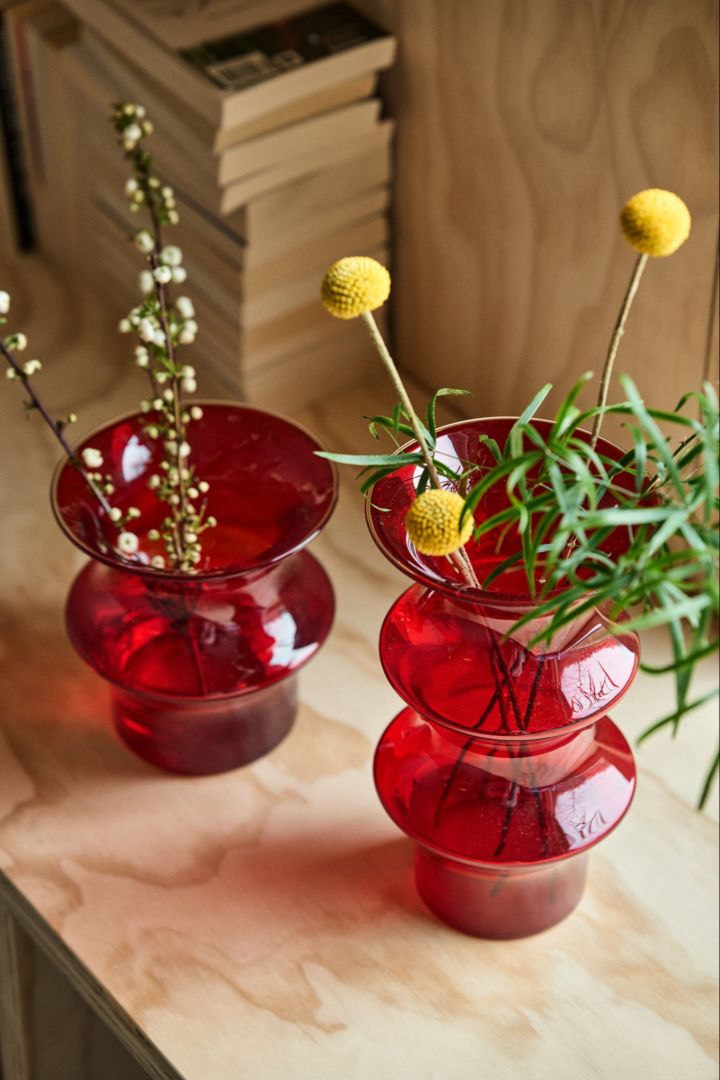 To røde Pagod-vaser står ved siden av hverandre på en kryssfinerbenk.
