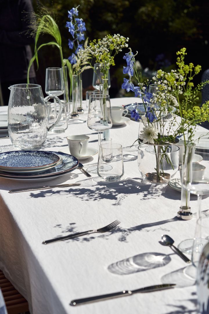 Legg til interessante detaljer på borddekkingen til svensk midtsommer med en samling vaser og blå og hvite blomster.