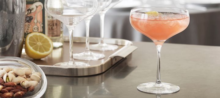 En alkoholfri drink med grapefruktjuice servert i et Cabernet cocktailglass fra Holmegaard. Drikken står på en kjøkkenbenk, med cocktailutstyr synlig i bakgrunnen.