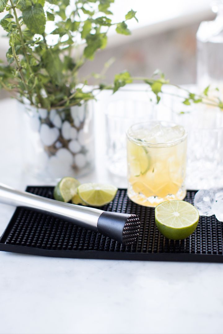 Mocktail: En Virgin Caipirinha med lime og brunt sukker står på en barmatte.