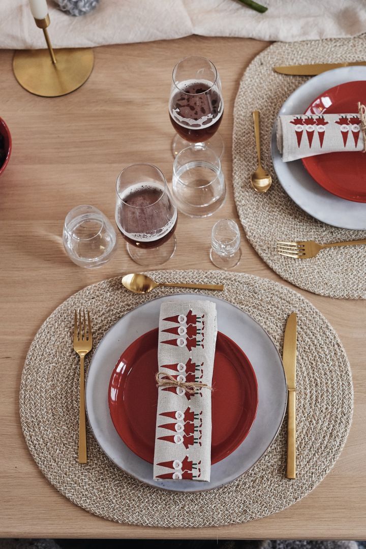 En enkel borddekking til jul, der kuverten består av blågrå middagstallerken, rød asjett og gullbestikk.