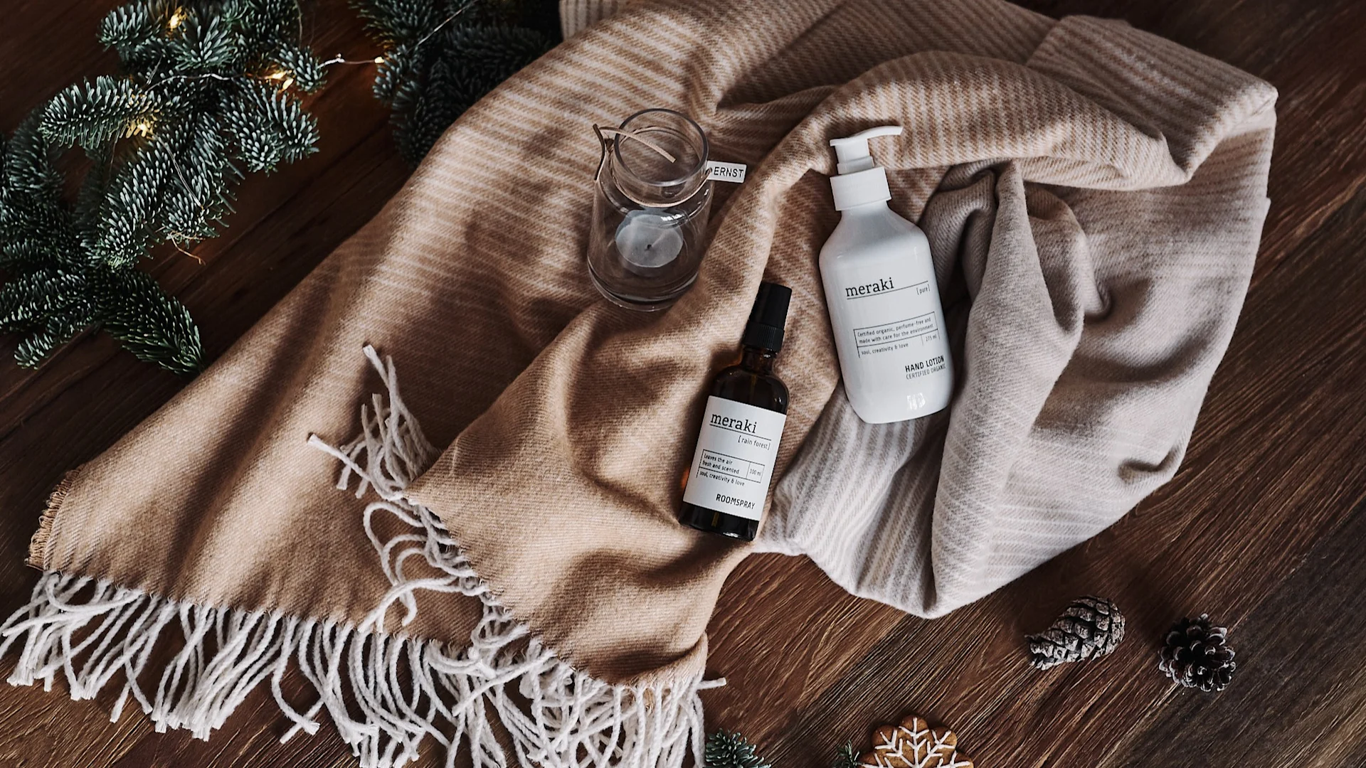 Håndkrem og lyslykt ligger på et bomullpledd som kommer til å brukes for å gjøre gaveinnpakkingen miljøvennlig.