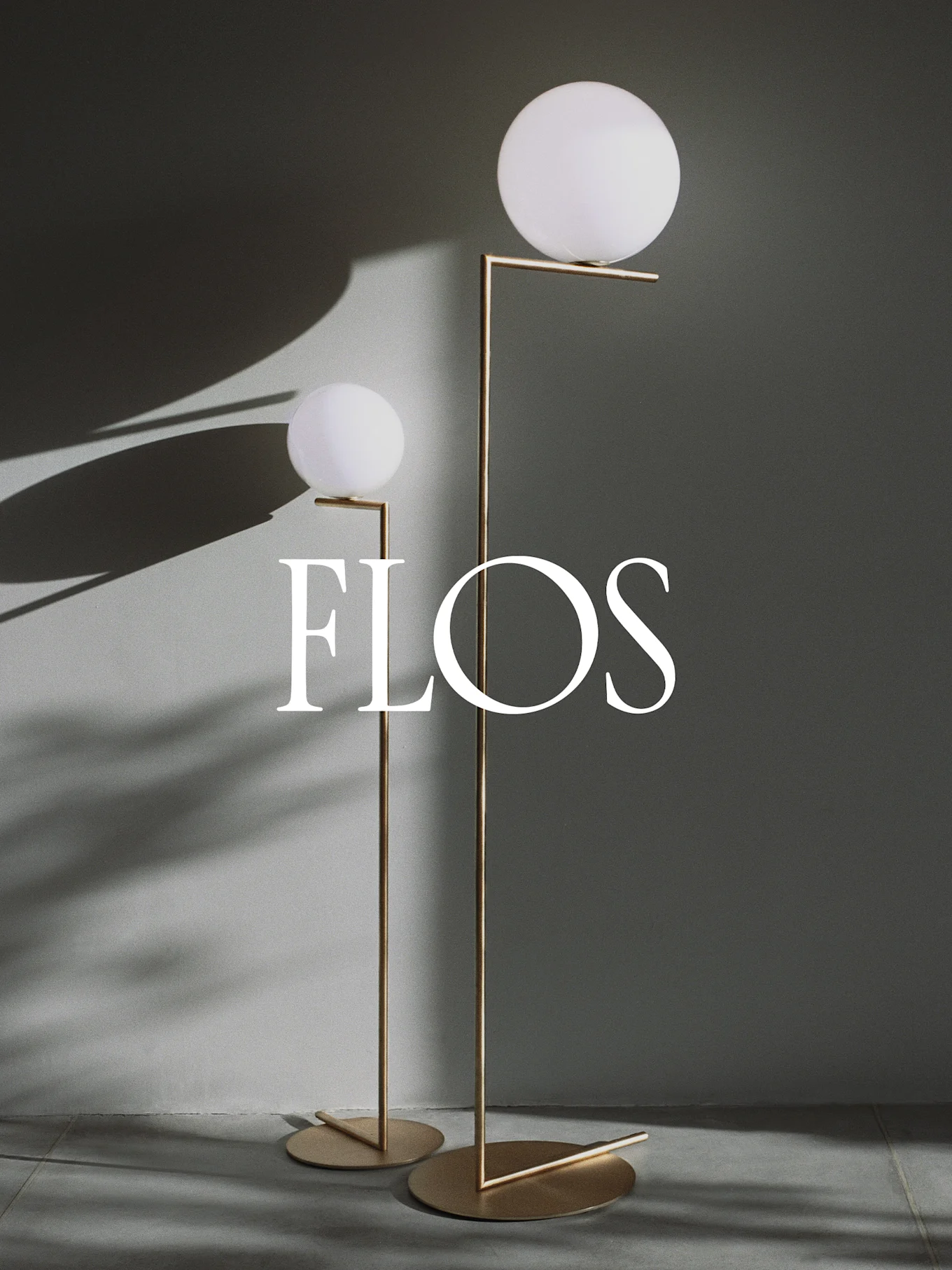 To moderne gulvlamper med sfæriske hvite diffusere og gullfargede metallrammer, med Flos-logoen.