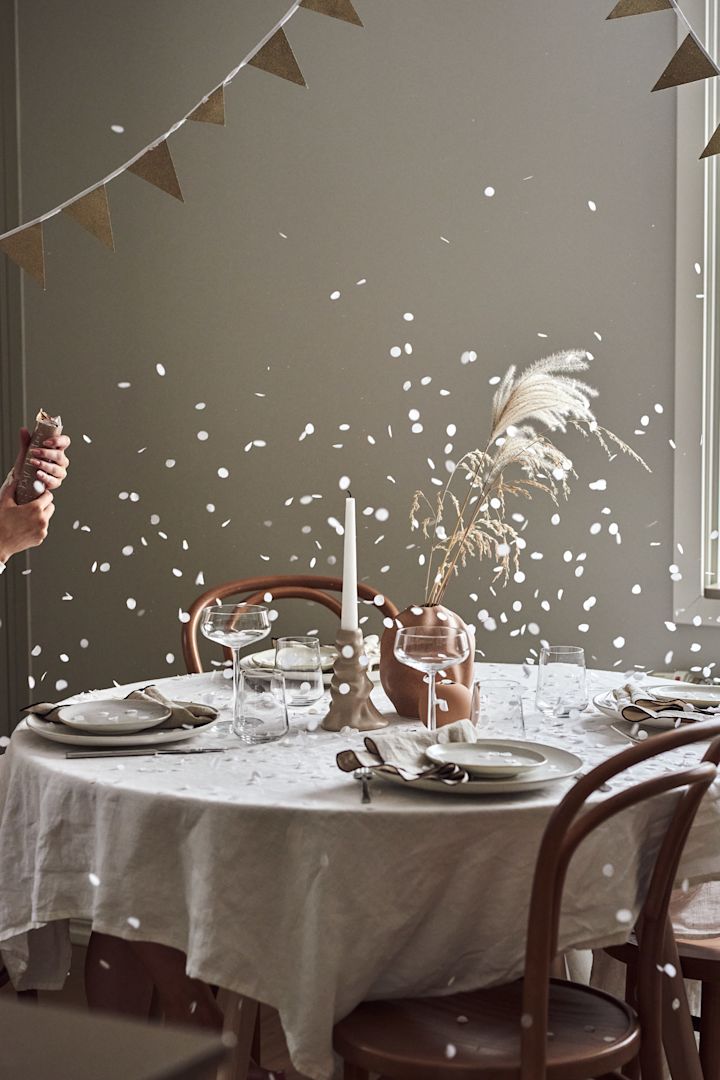 Hvordan arrangere en fest med den perfekte stemningen, her ser du et dekket bord med en nylig eksplodert party popper og konfettien som legger seg på bordet.