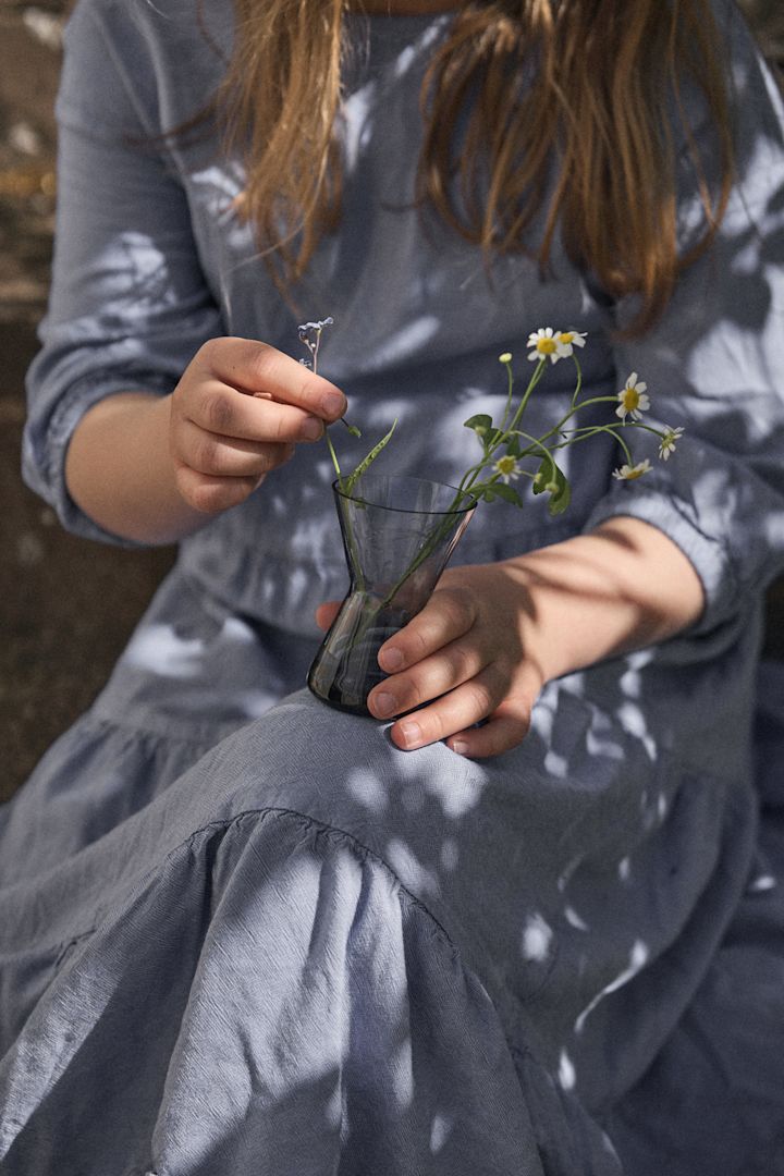 Midtsommer Orrefors - her ser du en kvinne i blå kjole som holder en vase fra kollesksjonen Midtsommer fra Orrefors.