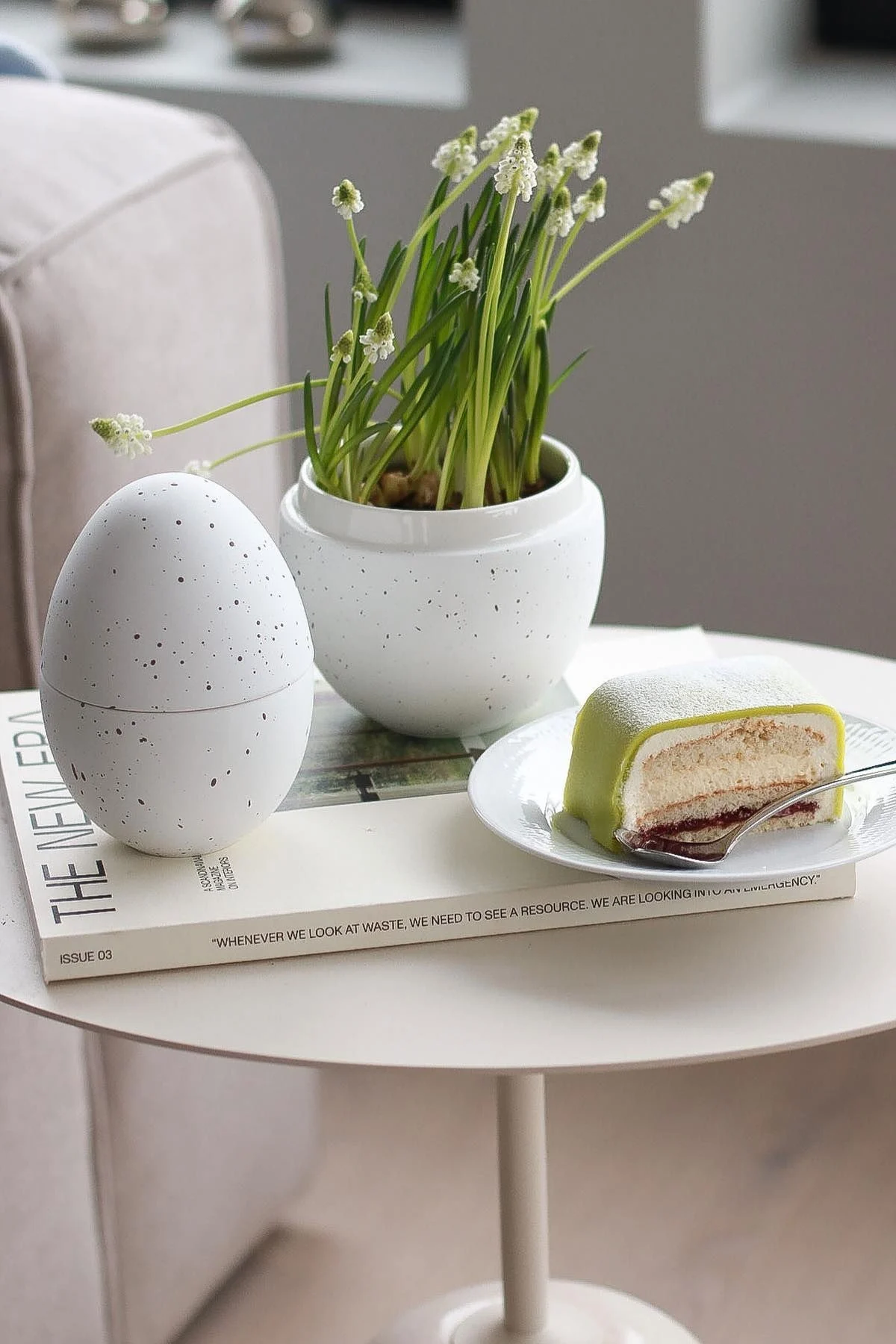 Påskepynt: På et sidebord står den hvite bonbonnieren med blomster fra Cooee Design, ved siden av en tallerken med prinsesstårta, hjemme hos @picsbyellen.