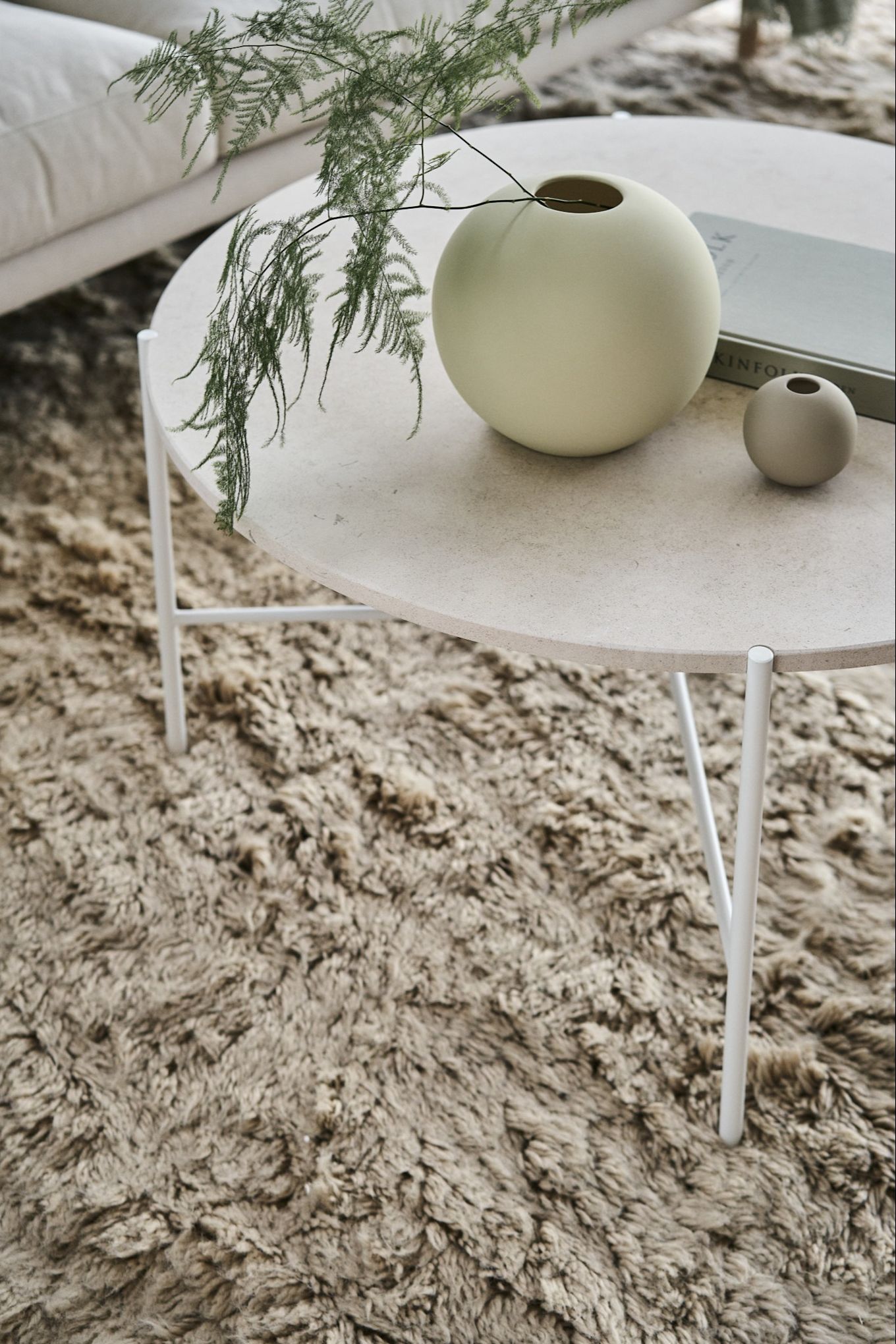 Den ikoniske Ball-vasen i skall og sand fra Cooee Design på et salongbord i en stue i skandinavisk stil.