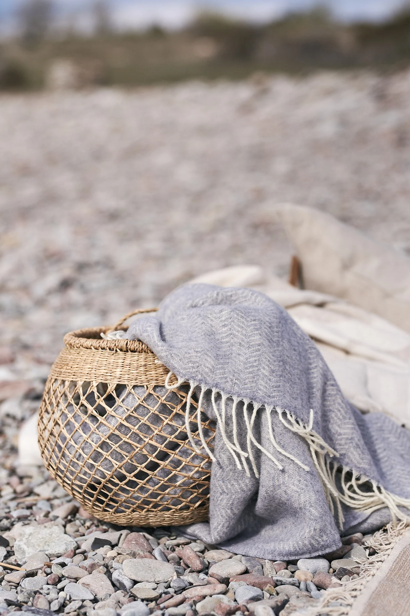 Oppbevaringskurv i sjøgress med blått ullteppe i.