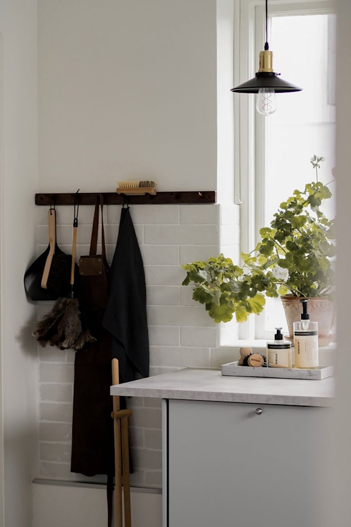 Mindre pendellamper gir spotlight på kjøkkenet. Her ser du Disc Mini pendellampe i svart fra Globen Lighting hengende på et kjøkken foran et vindu.