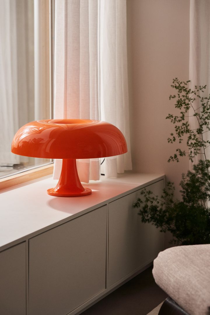 Sats på farge og la deg inspirere av årets interiørtrender 2024, her Nesso fra Artemide i vinduskarmen i trendy oransje farge.