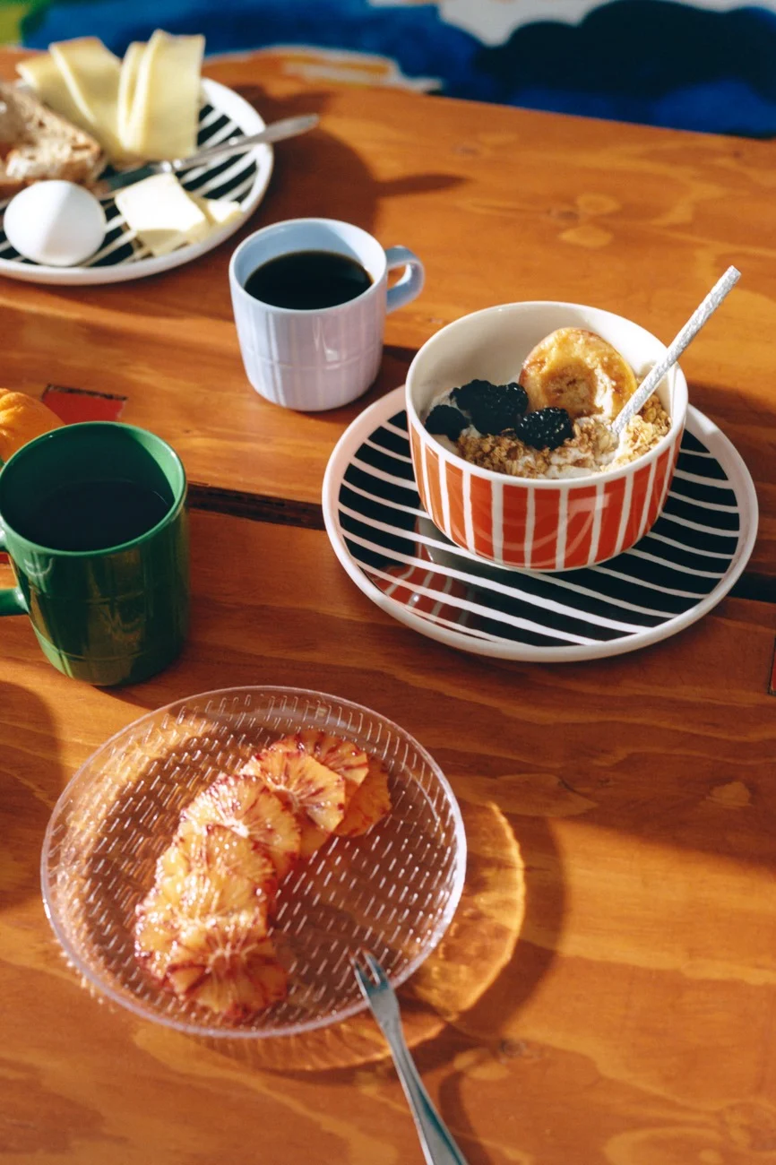 Frokost på trebord med stripete servise, kaffe, havregryn, ost, brød, egg og blodappelsinskiver.