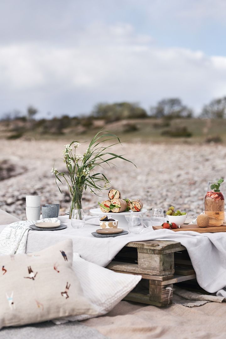 En luksuriøs piknik på stranden på paller, med puter og enkel piknikmat.